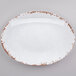 A white oval melamine platter with brown speckled edges.