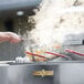 A person cooking food in a Crown Verity portable outdoor fryer on a counter.