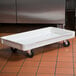 A white fiberglass MFG Tray dough proofing box dolly with black wheels.