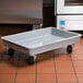 A gray MFG Tray fiberglass dough proofing box dolly with black wheels.