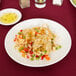 A Libbey bright white porcelain plate with rice and vegetables on a table.