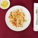 A Libbey Porcelana coupe plate with rice and vegetables, a spoon, and a fork on a table.