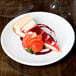 A slice of cheesecake with strawberries on a Libbey Porcelana coupe plate.