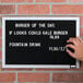 A person holding a black Aarco felt board with white text that says "Burger of the Day"