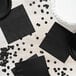 A table with black napkins and confetti.