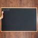 A person writing "specials" on a black Aarco chalk board.