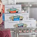 A woman holding a stack of Choice Safecut foodservice film boxes.