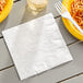 A white Creative Converting 3-ply paper dinner napkin on a table with a plate of spaghetti and a fork.