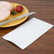 A plate with food and a white Creative Converting 3-ply guest towel on the table.