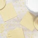 A table with a Creative Converting ivory napkin and yellow plate.