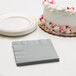 A white cake with red sprinkles next to a stack of Shimmering Silver beverage napkins.