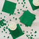 A table with emerald green Creative Converting beverage napkins and cups of liquid.