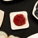 A Eco-gecko palm leaf bowl with fruit and jam on a table.