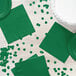 A white table with green napkins and confetti.