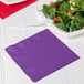 A purple Creative Converting luncheon napkin next to a plate of salad.