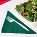 A plate of salad with strawberries and nuts on a hunter green 1/4 fold luncheon napkin.