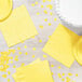 A table with yellow paper plates and Creative Converting Mimosa Yellow napkins.