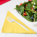 A plate of salad with strawberries, nuts, and a Creative Converting Mimosa Yellow luncheon napkin.