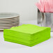 A stack of Creative Converting Fresh Lime Green 3-ply luncheon napkins on a table.