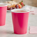 Two pink Creative Converting paper hot cups filled with a hot drink.