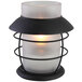 A white Sterno Hyannis frost lamp with a lit candle inside.