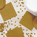 A table with a white plate, yellow napkin and confetti.