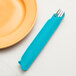A Bermuda Blue Creative Converting 3-ply paper dinner napkin with a fork on a plate.