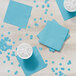 A white table with a group of blue Creative Converting pastel blue beverage napkins and drinks.