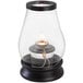 A Sterno Draper clear glass lantern with a flame inside.