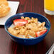 A Carlisle Dallas Ware cafe blue melamine bowl filled with cereal and milk with strawberries.