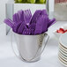 A bucket of purple plastic forks.