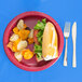 A Creative Converting burgundy paper plate with a sandwich and chips on it with a fork.