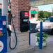 A black Commercial Zone Vue-T-Ful Isle windshield washing service center with a red sign and paper towel dispenser next to a gas pump.