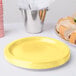 A stack of Creative Converting Mimosa Yellow paper plates.