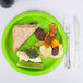 A sandwich on a Creative Converting Fresh Lime Green paper plate.