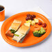 A sandwich cut in half on a Sunkissed Orange oval paper platter.