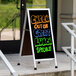 An Aarco narrow aluminum A-frame sidewalk sign with a black marker board.