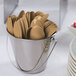 A bucket filled with brown plastic spoons with black lines.