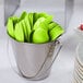 A bucket of Creative Converting Fresh Lime Green plastic spoons.