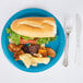 A turquoise blue Creative Converting paper plate with a sandwich and potato chips.