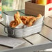 An American Metalcraft stainless steel metal tub filled with fried chicken on a table.