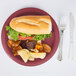 A Creative Converting burgundy paper plate with a sandwich, potato chips, and a fork.