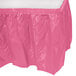 A Candy Pink plastic table skirt with a ruffle.