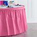 A table with a Creative Converting candy pink plastic table skirt and cupcakes.