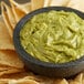 A bowl of guacamole with tortilla chips.