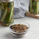 A jar of Regal Old Fashion Pickling Spice next to a bowl of pickles.