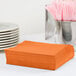 A stack of Sunkissed Orange luncheon napkins on a table.