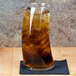 A Libbey Bravura tumbler filled with brown liquid and ice on a table.