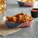 A paper food tray of chicken wings and fries with a USA flag.