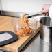 A bowl of spaghetti being poured into a Rubbermaid food storage container.